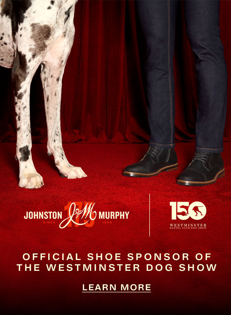 Lower half a white spotted Great Dane standing next to a man, which only shows his jeans and shoes. The banner states that Johnston & Murphy is the offical shoe sponsor of the Westminster Dog show.
